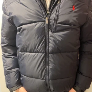 Mörkblå dunjacka från Ralph Lauren - Säljer en snygg mörkblå dunjacka från Ralph Lauren med dragkedja och broderad logga i rött på bröstet. Jackan har långa ärmar och är perfekt för kyligare väder. Fler bilder går och fixa. PRISET KAN DISKUTERAS! 