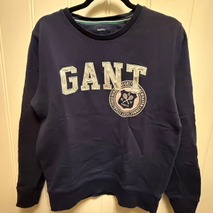 Mörkblå tjocktröja från GANT - Hej! Säljer en  mörkblå tjocktröja från GANT. Tröjan har långa ärmar och rund halsringning. 