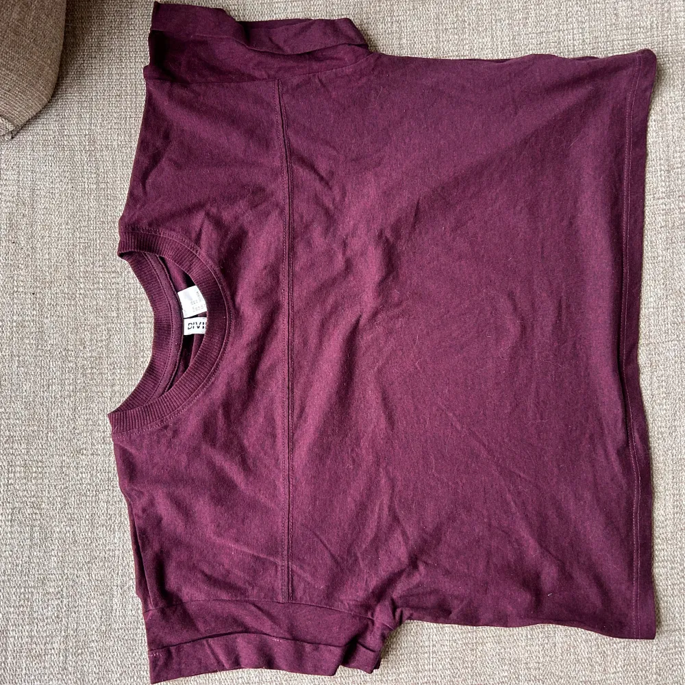 Säljer en lila kortärmad topp från Divided i bomull/polyester. Toppen har en avslappnad passform med korta ärmar och lite kortare i midjan . Stl xs och i mycket bra skick. Perfekt för en casual look.. Yläosat.