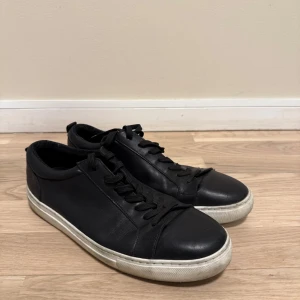 Svarta sneakers - Snygga svarta sneakers i skinn med snörning och vit sula. Perfekta för en stilren look. De har en klassisk design som passar till det mesta. Pris kan diskuteras.