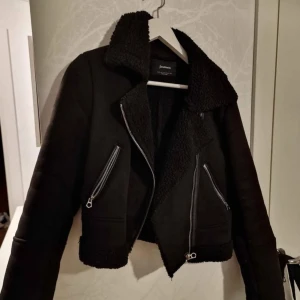 Svart jacka från Stradivarius  - Snygg svart jacka från Stradivarius med dragkedja och fuskpälsdetaljer. Jackan har en klassisk krage och är perfekt för kyligare dagar. Den har en stilren design med två fickor framtill.