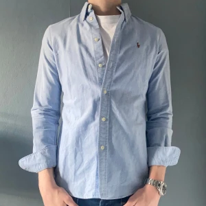 Ralph Lauren skjorta - Säljer en stilren ljusblå skjorta från Ralph Lauren i storlek XS. Säljer pga att den är för liten. Passar dig som är ca 155-170cm. Hör av dig vid frågor och funderingar!