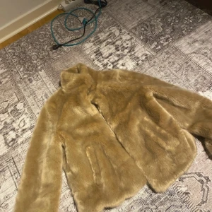 Beige pälsjacka från Pull&Bear - Säljer en snygg beige pälsjacka från Pull&Bear. Jackan har en mjuk och fluffig yta med långa ärmar och en stilren design. Perfekt för att hålla sig varm och trendig under kyliga dagar. 🧥✨