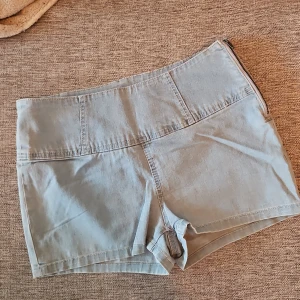 Ljusblå shorts med dragkedja - Snygga ljusblå shorts i jeansmaterial med hög midja och dragkedja på sidan. Perfekta för sommardagar med två bakfickor för extra stil och funktionalitet.