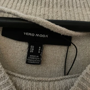 Beige stickad tröja från Vero Moda - Mysig beige stickad tröja från Vero Moda. Tröjan har en rund halsringning och långa ärmar med ribbade muddar. Perfekt för kyliga dagar.