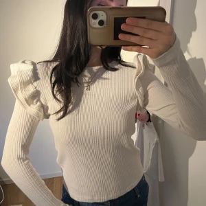 Zara tröja med volanger - Snygg vit ribbad tröja med volanger på axlarna. Långa ärmar o tight passform, från Zara💌