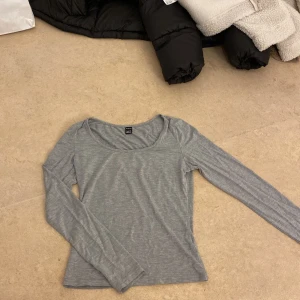 Grå långärmad topp från H&M - Säljer en stilren grå långärmad tröja. Perfekt för lager-på-lager eller som den är. Mjuk och bekväm med en rund halsringning. Skriv!🫶🏼❤️