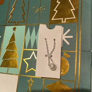 Silverfärgat halsband med pärldetalj - Elegant silverfärgat halsband med en vacker pärldetalj. Perfekt för att ge en stilren touch till din outfit. Kedjan är fin och smidig, vilket gör den bekväm att bära.