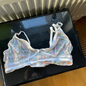 Blommig spets-bh - Säljer en söt blommig bh med spetsdetaljer. Den har justerbara axelband och hakknäppning bak. Perfekt för en romantisk look.