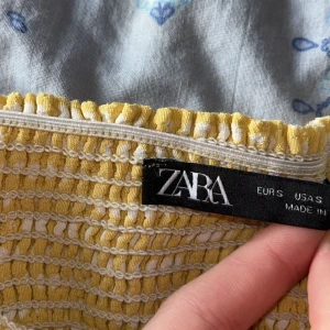 Gul prickig tubtopp från Zara - Säljer en söt gul tubtopp från Zara med vita prickar. Toppen har smala axelband och en dragkedja på sidan 