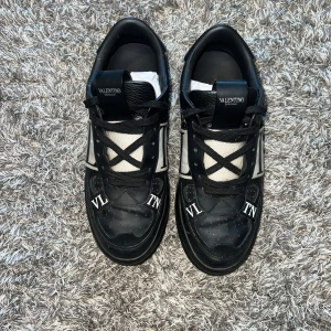 Valentino sneakers - Snygga svarta sneakers från Valentino med vita detaljer och VLTN-logga. Skorna har snörning och en stilren design som passar perfekt för en trendig look.