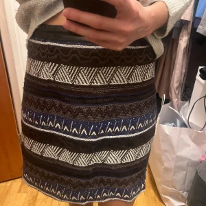 Mönstrad kjol i blått och svart - Snygg kortkjol med ett unikt mönster i blått, svart och vitt. Kjolen har en normal passform och är perfekt för att ge din outfit en bohemisk touch.