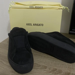 Axel Arigato clean 360 laceless  - Snygga svarta sneakers från Axel Arigato med en stilren design. Skorna har en diskret logga och är tillverkade i ett material som ger en lyxig känsla. Perfekta för en minimalistisk look.
