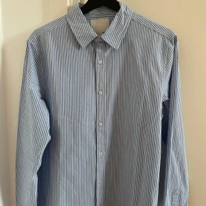 Blå- och vitrandig skjorta från Lager 157 - Blå- och vitrandig skjorta från Lager 157 i storlek S. Nyskick, prislappen sitter kvar på plagget!