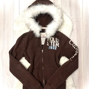 brun hollister fur zip up - fuskpälsen har blivit handsydd därav FAST pris! nackdelen är att hår från pälsen fastnar på plagget (men kan såklart borstas bort) men annars är koftan jätte snygg! 🐾varan är inte din före du klickar på KÖP NU. 🎀endast handtvätt med ljummet vatten då tvättmaskin + torktumlare förstör pälsen! 