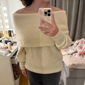 creamwhite offshoulder tröja från H&M - Säljer en mysig creamwhite offshoulder tröja från H&M. Tröjan är stickad med långa ärmar och har en bred krage som ger en avslappnad look. Perfekt för kyliga dagar! I bra skick