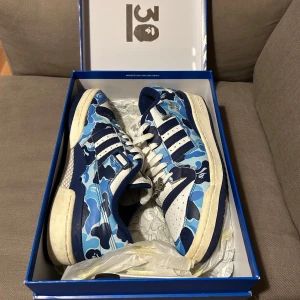 Adidas x A Bathing Ape sneakers - Snygga Adidas sneakers i samarbete med A Bathing Ape. Skorna har ett blått camouflage-mönster med vita och mörkblå . Storlek är 45 men skulle säja att dom sitter som 44.Ny pris är runt 3800