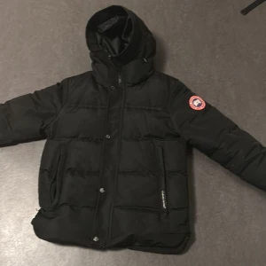 Canada goose jacka - Säljer en svart dunjacka från Canada Goose med huva och broderad logga på ärmen. Jackan har dragkedja och knappar framtill samt två fickor. Perfekt för kalla vinterdagar. Priset är ej hugget i sten självklart kan det diskuteras. Vid frågor är det bara att skriva. Storleken är S passar dock perfekt om man har M.