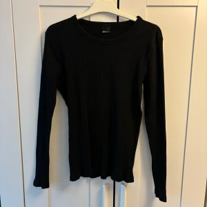 Svart ribbad tröja från Gina Tricot - Fin tröja från Gina Tricot! Säljer då jag inte avänder längre, tröjan är i fint skick! Hållbart bomull, en del av deras hällbarhetsprogram "the good project" Säljer en stilren svart ribbad tröja från Gina Tricot. 