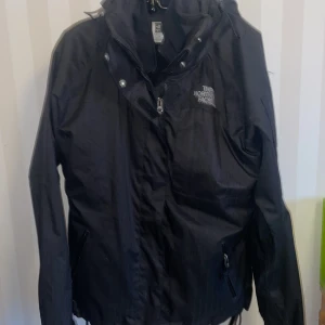 The North Face Svart jacka  - Säljer en svart triclimate jacka från The North Face med dragkedja och huva består av 2 delar som är separata en termo del plus en vindjacka , använt några gånger i nyskick! Jackan har långa ärmar och är perfekt för blåsiga & kalla dagar. Den är tillverkad i ett slitstarkt material och har en stilren design med logotyp på bröstet.