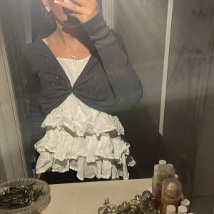 Mörkgrå bolerotopp - Jättesöt bolero som ej kommer till användning. Den är mörkgrå och har fina ribbade detaljer på sig. Boleron har långa ärmar och är superfin att ha över en topp eller linne. 