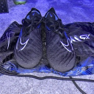 Nike phantom gx elite blue and black - Fantisktiska forbollskor från Nike. Med en snygg svart och blå blandning men även lite metall silver detaljer. Nypris var 3000 kr. Har ej några sulor