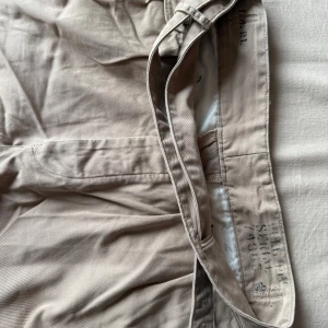 Beige byxor från Polo Ralph Lauren - Säljer ett par stilrena beige byxor från Polo Ralph Lauren. Byxorna har en klassisk design med normal passform och är tillverkade i ett bekvämt bomullsmaterial. Perfekta för en avslappnad men ändå snygg look.