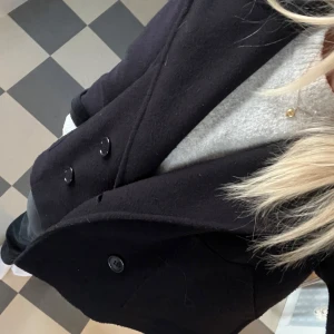 mörkblå kappa - INTRESSEKOLL!!! Snygg mörkblå kappa med dubbelknäppning och klassisk design. Perfekt för kyligare dagar med sin stilrena look och bekväma passform. sparsamt använd