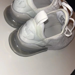 Vita Nike sneakers - Snygga vita Nike sneakers med snörning och en stor synlig luftkudde i sulan. Perfekta för en sportig look med stilren design.