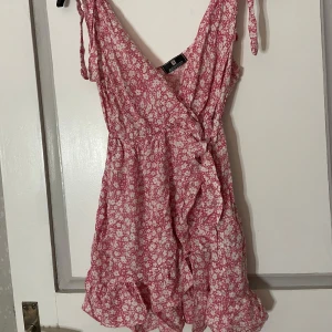 Rosa blommig klänning från Alexander - Charmig rosa klänning med blommigt mönster från Alexander. Den har volangdetaljer och knytband vid axlarna. Perfekt för sommarens varma dagar.  Köpt i spanien för 500kr och har endast använts 1 gång🤗