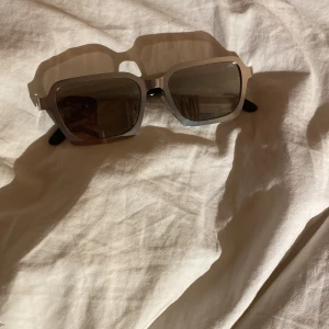 Stilrena solglasögon med silverram - Snygga solglasögon med en fyrkantig form och silverfärgad ram. De har mörka linser och svarta skalmar, vilket ger en modern och elegant look. Perfekta för soliga dagar.