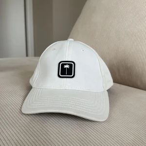 Vit keps från Palm Angels - Snygg vit keps från Palm Angels med en broderad palm på framsidan. Kepsen har en klassisk design med en normal passform och palm angels broderat på baksidan. Ny pris 2000kr