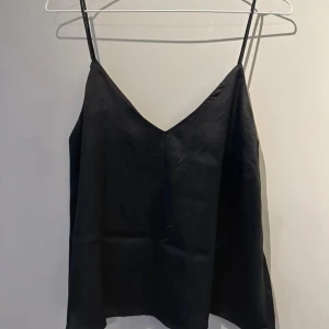 Svart linne i satin  - Snygg svart linnetopp i satin från Lager157 med tunna axelband och v-ringning. 