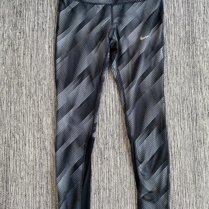 Nya gråa och svarta mönstrade träningstights i strl M från Nike - Nya gråa och svarta mönstrade träningstights i strl M från Nike.  Nya, aldrig använda  Mått Midjan: ca 37 cm Från grenen och ner: ca 74 cm  Polyester och elastan  Kommer från ett djur och rökfritt hem. 
