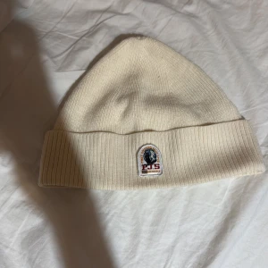 Beige mössa från Parajumpers - Snygg beige mössa från Parajumpers med ribbad design och broderad logotyp framtill. Perfekt för kyliga dagar.