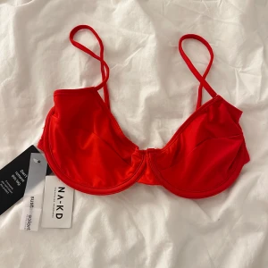 Röd bikiniöverdel från NA-KD - Snygg röd bikiniöverdel från NA-KD i färgen Lollipop Red. Den har tunna axelband och en stilren design med sömdetaljer. Storlek 75D endast testad!