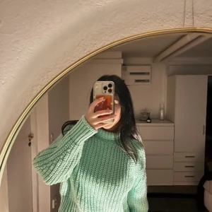 Mintgrön stickad polotröja - Säljer en mysig mintgrön stickad polotröja med ribbad design. Perfekt för kyliga dagar med sin höga krage och långa ärmar. Tröjan har en avslappnad passform och är ett måste i garderoben för höst och vinter.