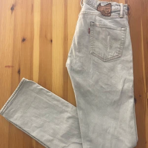 Ljusa Levi's Jeans - Säljer ett par ljusa Levi's jeans med klassisk femficksdesign och knappgylf. De har regular straight passform. Märkeslappen bak är krympt, annars ok skick.