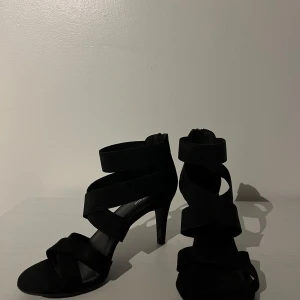 Svarta klackskor med dragkedja - Snygga svarta klackskor med breda remmar och dragkedja baktill. Perfekta för en kväll ute eller en speciell tillställning. Är enbart använda en gång. Klacken är ca 8 cm.