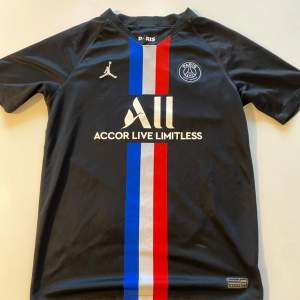 Snygg svart PSG-tröja med Mbappé 7 på ryggen. Framsidan har det ikoniska Paris Saint-Germain-emblemet och Jordan-loggan, samt ränder i blått, vitt och rött. Perfekt för fans av både PSG och Mbappé! Storleken är 158-170, XL i barnstorlek. Skick 7/10. Vid frågor och funderingar är det bara att kontakta
