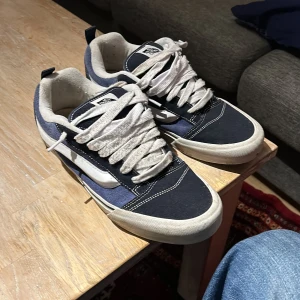 Blå och vita sneakers från Vans - Säljer ett Vans sneakers i blått och vitt. Skorna har en snygg design med ”gum” och snörning. Perfekta för en avslappnad stil.