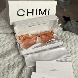 Rosa solglasögon från CHIMI - Snygga rosa solglasögon från CHIMI med transparent båge och matchande rosa linser. Perfekta för att ge en färgklick till din outfit. Kommer med originalförpackning och putsduk.