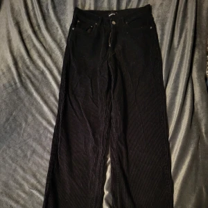 Svarta manchesterbyxor från Gina Tricot - Snygga svarta manchesterbyxor från Gina Tricot i storlek 34. Byxorna har en klassisk design med hög midja och raka ben, perfekt för en stilren look. De är tillverkade i mjukt manchestertyg som ger en skön känsla.