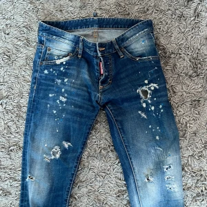 Dsquared2 Jeans - Snygga blå jeans från DSQUARED2 med slitna detaljer och en cool, distressed look. De har en klassisk femficksdesign och en knappgylf. Perfekta för en avslappnad stil med en touch av edge.
