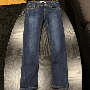 Mörkblå jeans från Levi's - Säljer ett par snygga mörkblå Levi's jeans i bra skick. De har en klassisk femficksdesign med guldfärgade nitar och en knappgylf. Perfekta för både vardag och fest! 🕺passar längden 150-160cm
