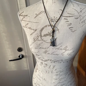 Brunt läderhalsband med berlocker - Snyggt brunt läderhalsband med två metallberlocker. Perfekt för en cool och avslappnad stil. Justerbar längd för att passa olika outfits. Passar både till vardags och fest! Maxlängd inklusive berlocker 42 cm.