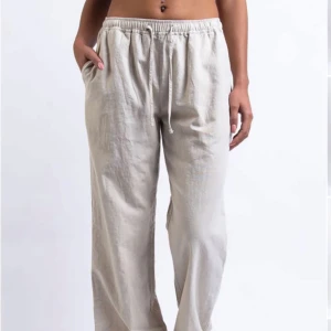 Beige linnebyxor - Säljer ett par superbekväma beige linnebyxor med loose fit. Byxorna har en elastisk midja med snörning för extra komfort. De är i mycket bra skick och väldigt bekväma byxor. Kan användas både som linnebyxor och mjukisbyxor hemma!