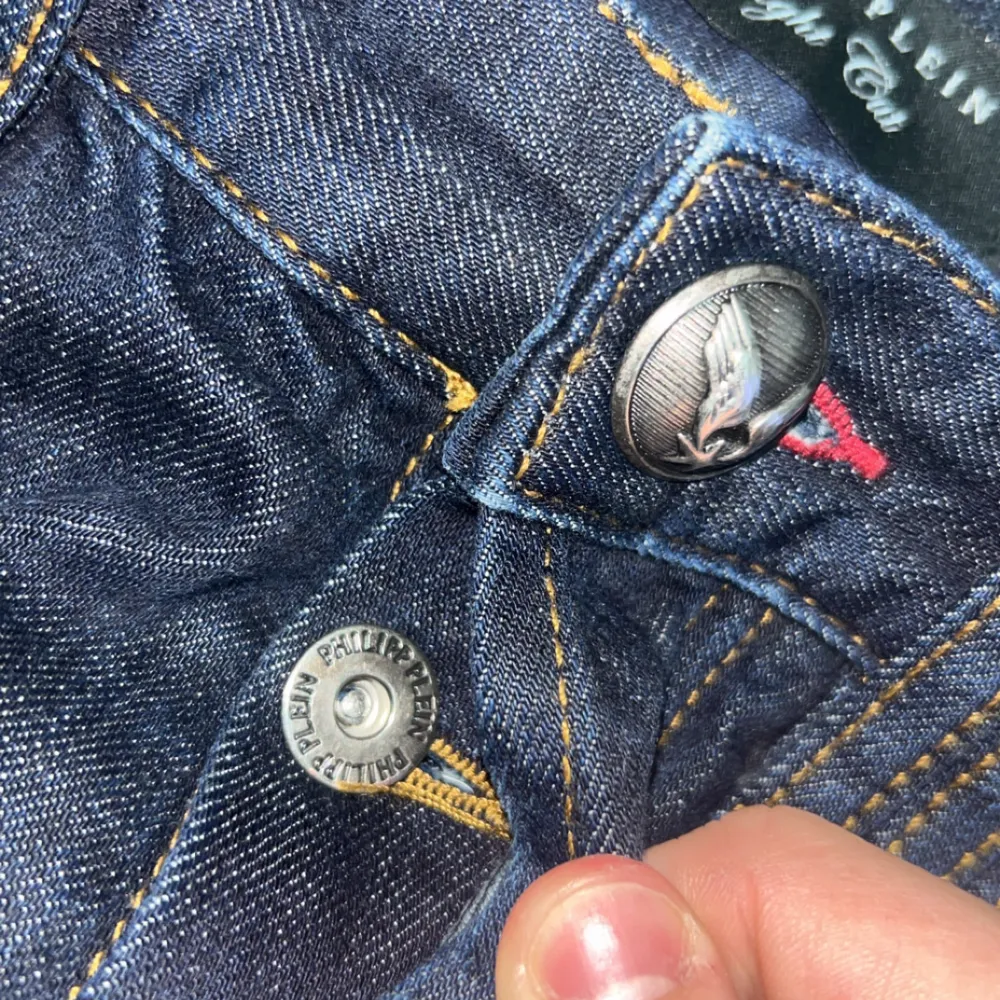 Snygga Philipp Plein jeans i mörkblå denim med coola detaljer som en unik knappdesign och logotyp på bakfickan. Tillverkade i Turkiet med en blandning av bomull och polyester för en bekväm passform. Perfekta för både vardag och fest!. Jeans & Byxor.