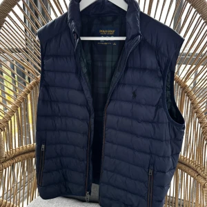 Ralph Lauren väst (Golf edt) - Snygg mörkblå dunväst från Polo Ralph lauren (Golf Edition) med dragkedja och broderad logga på bröstet. Perfekt för höst och vår, med quiltad design som ger en stilren look. Västen har en något större passform och är i mycket bra skick. Passar mig som har storlek L vanligtvis