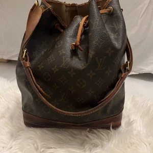Louis Vuitton noé väska  - Louis Vuitton noé väska, har defekter och skador på lädret. Den går att använda perfekt trots de och det har varit min favorit väska länge men nu måste jag tyvärr sälja den. Jag har fler bilder av den så är man intresserad skickar jag dem också. Det går att lämna in hos skomakare om man skulle vilja fixa lädret såklart. :) naturligvis äkta, köpt på Vestiaire. 